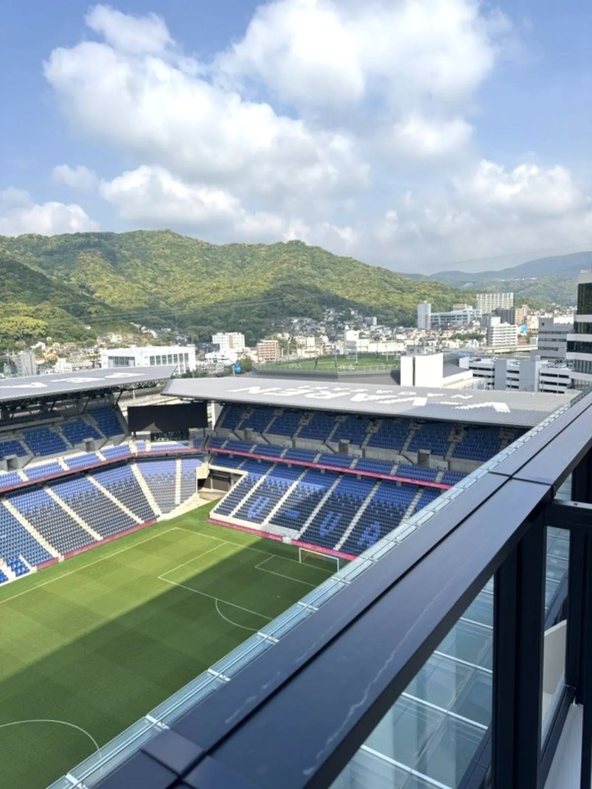 長崎スタジアムシティを上階から見下ろした眺め。ピッチと長崎の山並みが一望できる